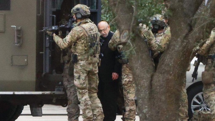 Shortly after 5 p.m., local time, authorities escort a hostage out of the Congregation Beth Israel synagogue in Colleyville, Texas, Saturday, Jan. 15, 2022. Police said the man was not hurt and would be reunited with his family. (Elias Valverde/The Dallas Morning News via AP)