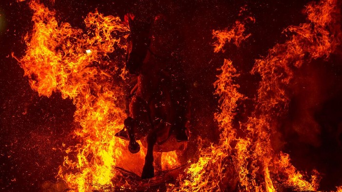 Tradisi Menembus Kobaran Api Untuk Menyucikan Kuda A man rides a horse through a bonfire as part of a ritual in honor of Saint Anthony the Abbot, the patron saint of domestic animals, in San Bartolome de Pinares, Spain, Sunday, Jan. 16, 2022. On the eve of Saint Anthony's Day, dozens ride their horses through the narrow cobblestone streets of the small village of San Bartolome during the