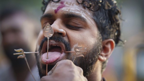  Seorang umat Hindu menusukan lidahnya dengan batang logam selama festival Thaipusam di Batu Caves, pinggiran Kota Kuala Lumpur, Malaysia, Selasa (18/1/2022).