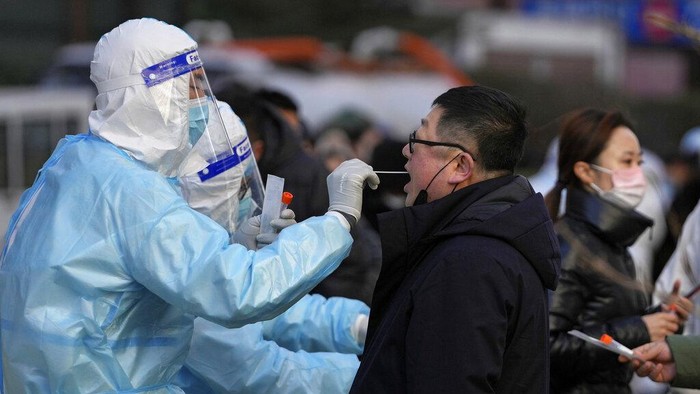 A man gets a throat swab for the COVID-19 test at a mobile coronavirus testing facility outside a commercial office buildings in Beijing, Monday, Jan. 17, 2022. Beijing's first reported case of the omicron variant has prompted stepped-up measures in the nation's capital, just weeks before it hosts the Winter Olympic Games. (AP Photo/Andy Wong)