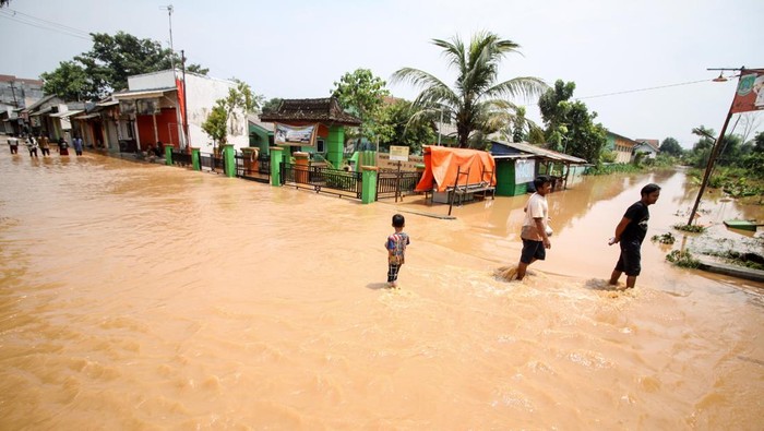 Belasan Desa di Kabupaten Pasuruan Kebanjiran Warga melintasi banjir di Desa Kedawung, Grati, Pasuruan, Jawa Timur, Selasa (18/1/2022). Hujan deras dengan intensitas tinggi tersebut mengakibatkan belasan desa di tiga kecamatan wilayah timur Kabupaten Pasuruan terendam banjir dengan ketinggian hingga satu meter. ANTARA FOTO/Umarul Faruq/foc.