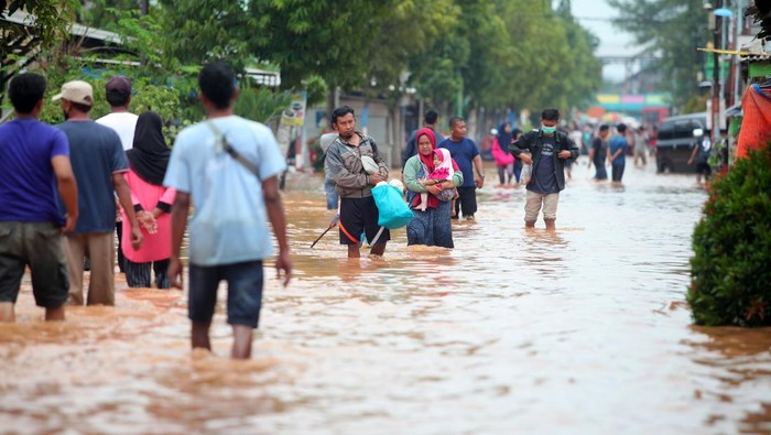 Belasan Desa di Kabupaten Pasuruan Kebanjiran Warga melintasi banjir di Desa Kedawung, Grati, Pasuruan, Jawa Timur, Selasa (18/1/2022). Hujan deras dengan intensitas tinggi tersebut mengakibatkan belasan desa di tiga kecamatan wilayah timur Kabupaten Pasuruan terendam banjir dengan ketinggian hingga satu meter. ANTARA FOTO/Umarul Faruq/foc.