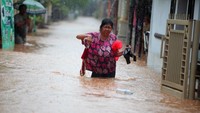 Warga melintasi banjir di Desa Kedawung, Grati, Pasuruan, Jawa Timur, Selasa (18/1/2022).