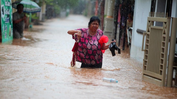 Belasan Desa di Kabupaten Pasuruan Kebanjiran Warga melintasi banjir di Desa Kedawung, Grati, Pasuruan, Jawa Timur, Selasa (18/1/2022). Hujan deras dengan intensitas tinggi tersebut mengakibatkan belasan desa di tiga kecamatan wilayah timur Kabupaten Pasuruan terendam banjir dengan ketinggian hingga satu meter. ANTARA FOTO/Umarul Faruq/foc.