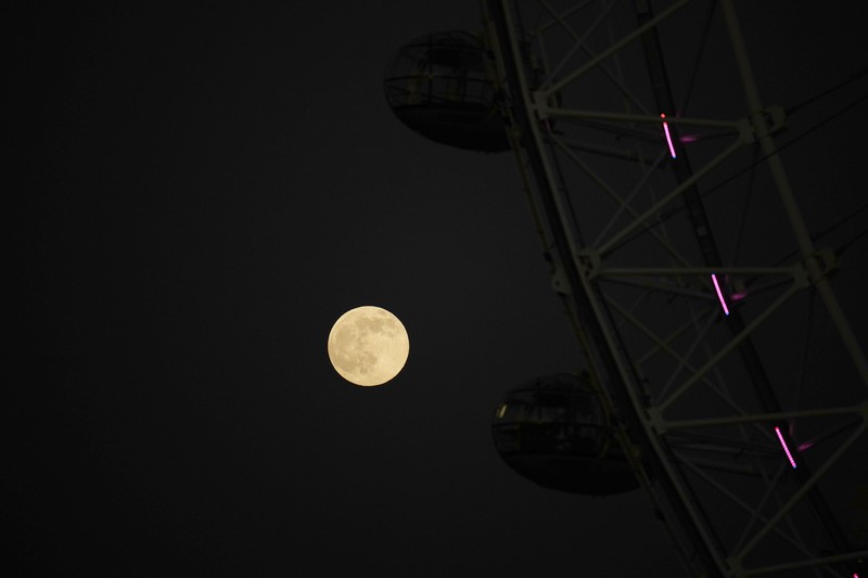 The first full moon of the year known as a Wolf Moon is seen behind different clock faces showing different times, with the correct time at right, as refurbishment work continues on the Elizabeth Tower, known as Big Ben, and the Houses of Parliament, in London, Monday, Jan. 17, 2022. (AP Photo/Matt Dunham)