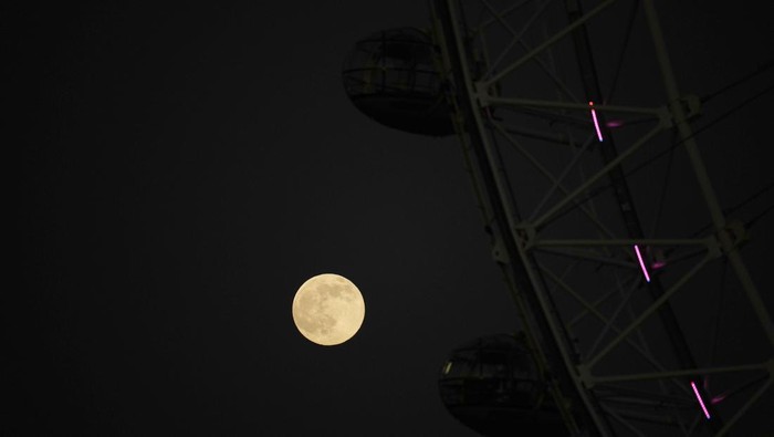The first full moon of the year known as a Wolf Moon is seen behind different clock faces showing different times, with the correct time at right, as refurbishment work continues on the Elizabeth Tower, known as Big Ben, and the Houses of Parliament, in London, Monday, Jan. 17, 2022. (AP Photo/Matt Dunham)