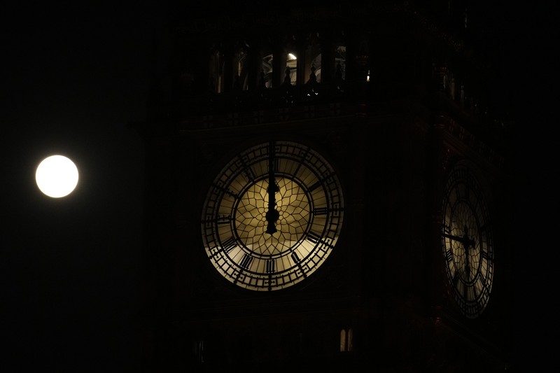 The first full moon of the year known as a Wolf Moon is seen behind different clock faces showing different times, with the correct time at right, as refurbishment work continues on the Elizabeth Tower, known as Big Ben, and the Houses of Parliament, in London, Monday, Jan. 17, 2022. (AP Photo/Matt Dunham)
