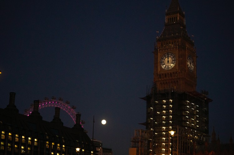 The first full moon of the year known as a Wolf Moon is seen behind different clock faces showing different times, with the correct time at right, as refurbishment work continues on the Elizabeth Tower, known as Big Ben, and the Houses of Parliament, in London, Monday, Jan. 17, 2022. (AP Photo/Matt Dunham)