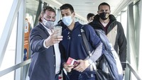 Petenis Novak Djokovic berfoto bersama seorang pria usai tiba di bandara Serbia. AP Photo/Darko Bandic.