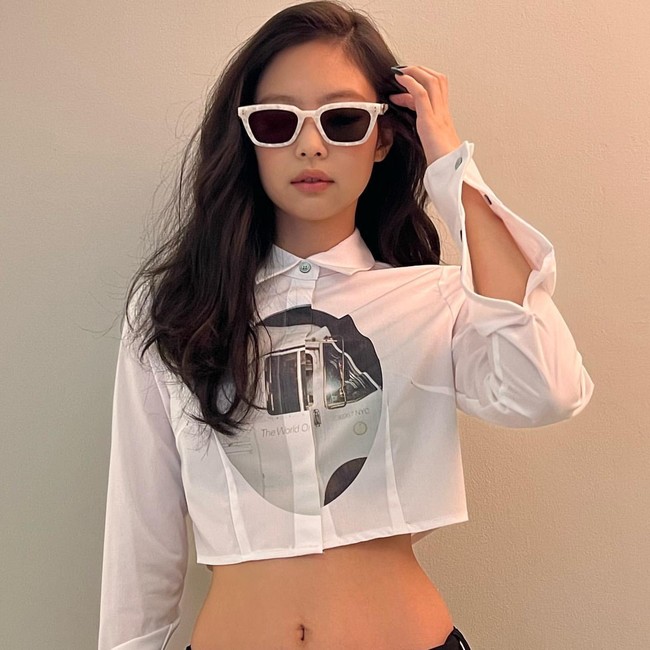 Jennie BLACKPINK memakai kemeja crop berwarna putih yang memamerkan otot perutnya. Dia membiarkan rambutnya tergerai dan memakai kacamata hitam, dengan frame berwarna senada. Foto: dok Instagram jennierubyjane.