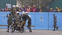 Sejumlah pekerja yang terlibat dalam pembangunan gedung parlemen baru India menyaksikan pasuka pertahan berlatih untuk pawai Hari Republik India di kawasan New Delhi, Senin (17/1/2022).