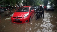 Pemotor menuntun kendaraan yang mogok akibat menerobos genangan di Jalan Bungur Besar, Kemayoran. Hujan deras di sini berlangsung sekitar 90 menit.