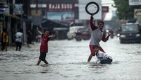Banjir di kawasan ini juga jadi arena bermain anak-anak.