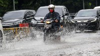 Pemotor menerobos genangan air di Jalan Medan Merdeka Timur, Jakarta Pusat.