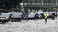 Tampak polisi tengah mengatur kendaraan yang menghindari genangan yang cukup dalam.