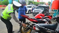 Anggota polisi menilang pengendara motor pengguna knalpot racing saat penertiban oleh jajaran Satlantas Polres Kudus, Kudus, Jawa Tengah, Senin (17/1/2022).