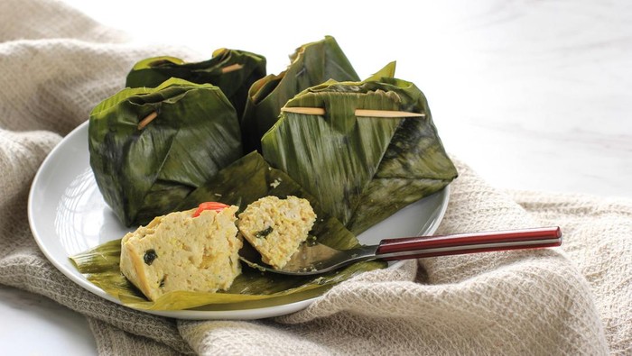 Pepes Tahu is Indonesian Spiced Tofu Wrapped with Banana Leaf and Steamed, Typically Indonesian Food from West Java (Sundanese). Steamed Tofu with Asian Basil, White Background