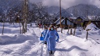 Fozia, depan dan Tasleema, petugas kesehatan Kashmir, membawa vaksin saat mereka berjalan di jalan yang tertutup salju setelah memberikan dosis kepada seorang wanita tua selama upaya vaksinasi COVID-19 di Budgam.