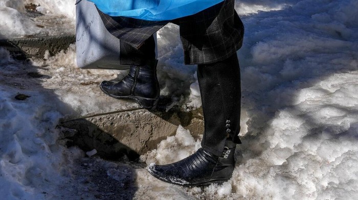 Masrat Farid, a healthcare worker, carries vaccines as she walks on a snow covered field after administering doses to young girls during a COVID-19 vaccination drive in Gagangeer, northeast of Srinagar, Indian controlled Kashmir, Jan. 12, 2022. (AP Photo/Dar Yasin)