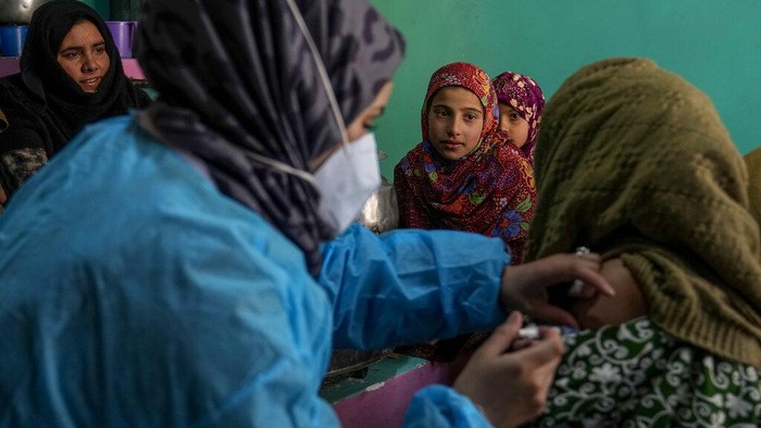 Masrat Farid, a healthcare worker, carries vaccines as she walks on a snow covered field after administering doses to young girls during a COVID-19 vaccination drive in Gagangeer, northeast of Srinagar, Indian controlled Kashmir, Jan. 12, 2022. (AP Photo/Dar Yasin)