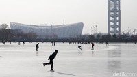Warga bermain ski dengan latar stadion sarang burung, di Beijing.