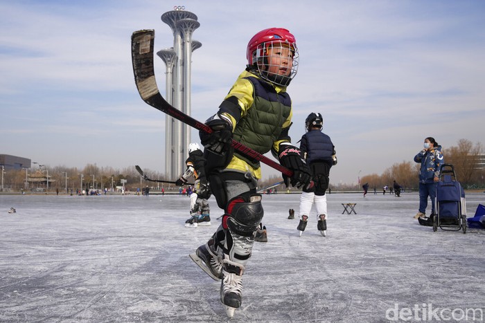 Residents play on a frozen pond surface near the iconic Bird's Nest Stadium in Beijing, China, Tuesday, Jan. 18, 2022. China has locked down parts of Beijing's Haidian district following the detection of three cases, just weeks before the capital is to host the Winter Olympic Games. (AP Photo/Ng Han Guan)