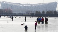 Warga bermain ski dengan latar stadion sarang burung, di Beijing. Ibu Kota negara China tersebut tengah disorot karena kenaikan angka positif Covid-19 Omicron menjelang pelaksaan olimpiade musim dingin.