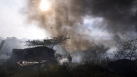 Seorang petugas pemadam kebakaran menyiram gubuk untuk mencegahnya terbakar selama kebakaran semak di lingkungan Banco San Miguel di Asuncion, Paraguay, Selasa, (18/1/2022).