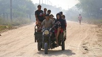 Sebuah sepeda motor roda tiga membawa penduduk setempat yang telah dievakuasi dari rumah mereka selama kebakaran semak di lingkungan Banco San Miguel.