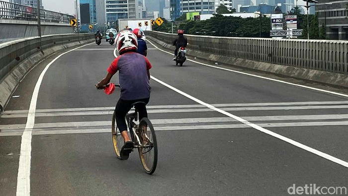 Gaya Pede Pesepeda Gowes Pakai Helm Motor Ada yang unik dengan pesepeda yang melintas di Jalan Gatot Subroto, Jakarta, Rabu (19/1/2022). Dia gowes sepedanya dengan menggunakan helm motor.