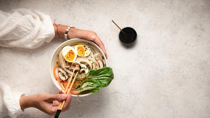 Flat lay of noodle bowls with hands