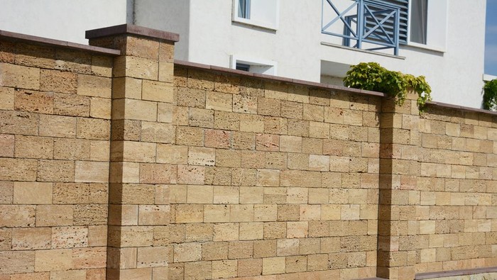 A close-up on a brown oyster shell foamed brick, limestone brick fence with support pillars.