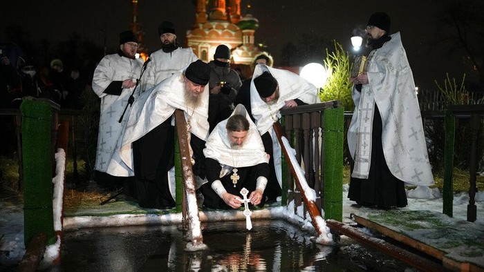 Tradisi Berendam Air Es di Rusia, Rayakan Hari Epiphany A Russian Orthodox priest blesses the icy water on Epiphany at the Church of the Holy Trinity in Ostankino near TV Tower in Moscow, Russia, Tuesday, Jan. 18, 2022. Across Russia, the devout and the daring are observing the Orthodox Christian feast day of Epiphany by immersing themselves in frigid water through holes cut through the ice of lakes and rivers. Epiphany celebrates the revelation of Jesus Christ as the incarnation of God through his baptism in the River Jordan. (AP Photo/Alexander Zemlianichenko)