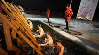 Petugas penyelamat mengamati umat Ortodoks Rusia berendam di air es selama perayaan Epiphany tradisional di St. Petersburg, Rusia, Rabu pagi, (19/1/2022). AP/Dmitri Lovetsky
