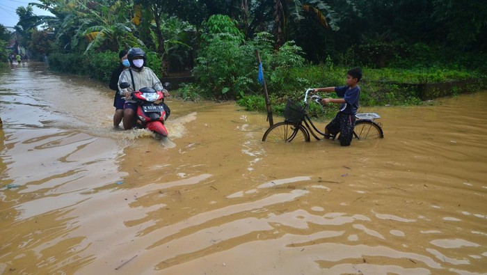 Sungai Meluap, Ratusan Rumah di Kudus Kebanjiran Dua anak melintasi jalan yang tergenang banjir di Desa Golantepus, Mejobo, Kudus, Jawa Tengah, Kamis (20/1/2022). Akibat intensitas hujan yang tinggi serta meluapnya Sungai Mrisen menyebabkan ratusan rumah dan jalan utama di desa itu terendam banjir. ANTARA FOTO/Yusuf Nugroho/tom.