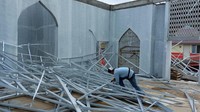 Seorang pria di tengah-tengah kerangka atap masjid yang baru saja dibongkar (dokumen istimewa).