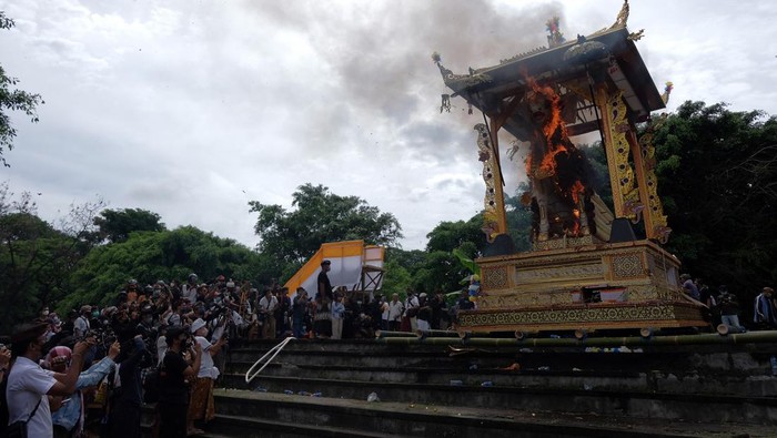 Wisatawan mengabadikan prosesi pembakaran peti berbentuk lembu yang berisi jenazah Raja Pemecutan XI Anak Agung Ngurah Manik Parasara saat upacara ngaben di Denpasar, Bali, Jumat (21/1/2022). Upacara ngaben Raja Pemecutan XI yang merupakan upacara berskala besar tersebut disaksikan ribuan warga dan wisatawan. ANTARA FOTO/Nyoman Hendra Wibowo/aww.
