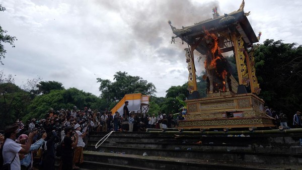 Wisatawan mengabadikan prosesi pembakaran peti berbentuk lembu yang berisi jenazah Raja Pemecutan XI Anak Agung Ngurah Manik Parasara saat upacara ngaben di Denpasar, Bali, Jumat (21/1/2022).   