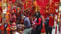 Orang-orang yang memakai masker wajah membeli dekorasi untuk merayakan Tahun Baru Imlek di Hong Kong.