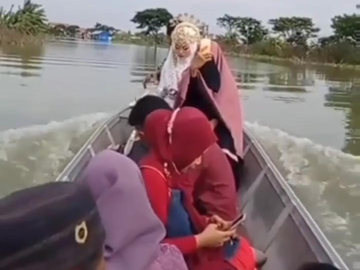 Video mempelai wanita mengarungi banjir beredar di media sosial. Pengantin itu naik perahu menuju tempat akad nikah, yakni KUA Kecamatan Turi.