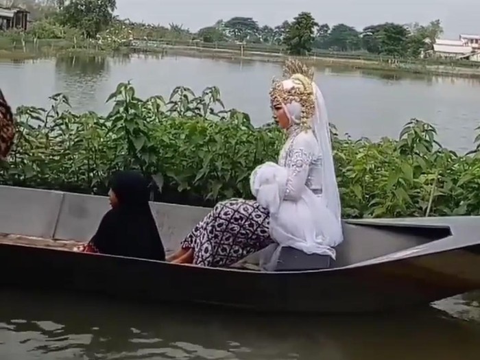 Video mempelai wanita mengarungi banjir beredar di media sosial. Pengantin itu naik perahu menuju tempat akad nikah, yakni KUA Kecamatan Turi.