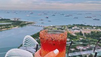 Foto saat memegang minuman ini diambil di Singapura. Minuman dingin yang tampak segar ini pun difoto dengan latar laut dan bangunan ikonik di Singapura.  Foto: Instagram @girleatworld