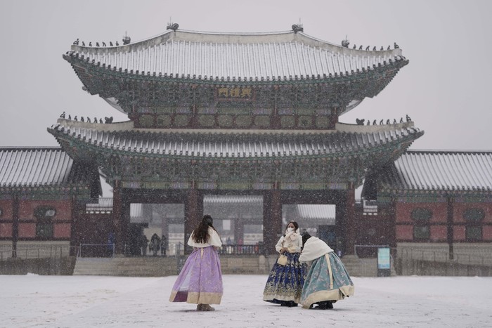 Visitors wearing face masks to help curb the spread of the coronavirus take a photo in the snow at the Gyeongbok Palace, one of South Koreas well-known landmarks, in Seoul, South Korea, Wednesday, Jan. 19, 2022. (AP Photo/Lee Jin-man)
