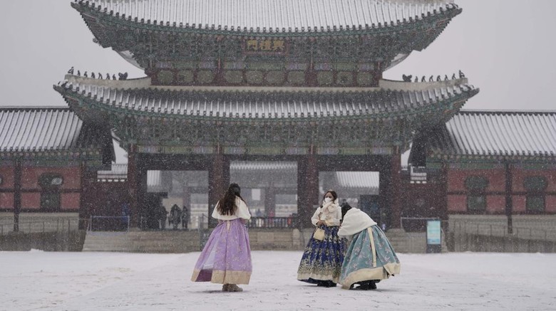 Visitors wearing face masks to help curb the spread of the coronavirus take a photo in the snow at the Gyeongbok Palace, one of South Koreas well-known landmarks, in Seoul, South Korea, Wednesday, Jan. 19, 2022. (AP Photo/Lee Jin-man)
