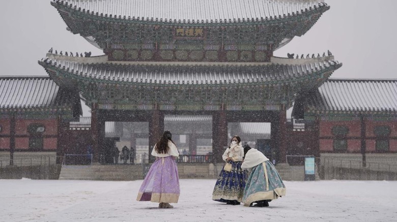 Berfoto di Gyeongbok Palace Korsel Visitors wearing face masks to help curb the spread of the coronavirus take a photo in the snow at the Gyeongbok Palace, one of South Koreas well-known landmarks, in Seoul, South Korea, Wednesday, Jan. 19, 2022. (AP Photo/Lee Jin-man)