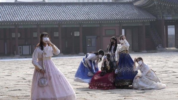 Siswa sekolah menengah yang mengenakan masker untuk membantu melindungi diri dari penyebaran virus corona berfoto di Istana Gyeongbok di Seoul, Korea Selatan, Minggu, 23 Januari 2022.
