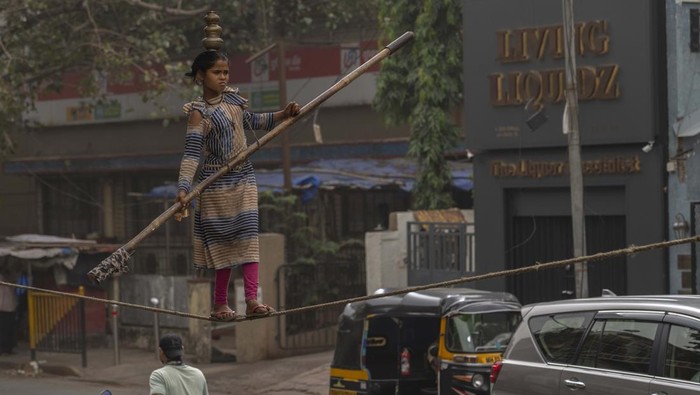 A girl walks a tight rope as she performs at a street to attract alms in Mumbai, India, Sunday, Jan. 23, 2022. (AP Photo/Rafiq Maqbool)