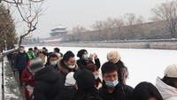 Wisatawan menikmati pemandangan di tepi sungai bersalju di belakang pintu gerbang Istana Kota Terlarang, Beijing, China, Sabtu (22/1/2022).   