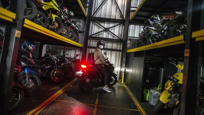 PARKIR SEPEDA MOTOR VERTIKAL DI JAKARTA Pekerja mengakses aplikasi saat akan menurunkan sepeda motor di Soul Parking, Kebon Kacang, Jakarta, Jumat (21/1/2022). Tempat parkir vertikal tersebut menerapkan sistem teknologi Compact Motor Storage atau sistem rak bersusun dengan lift barang sehingga bisa menyimpan lebih banyak motor di atas lahan sempit dan menjadi salah satu solusi untuk penataan parkir khusus motor di wilayah Ibu Kota Jakarta. ANTARA FOTO/Aprillio Akbar/aww.