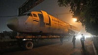 Pekerja menyingkirkan kabel yang melintang di jalan dan menghalangi proses pengiriman pesawat.
